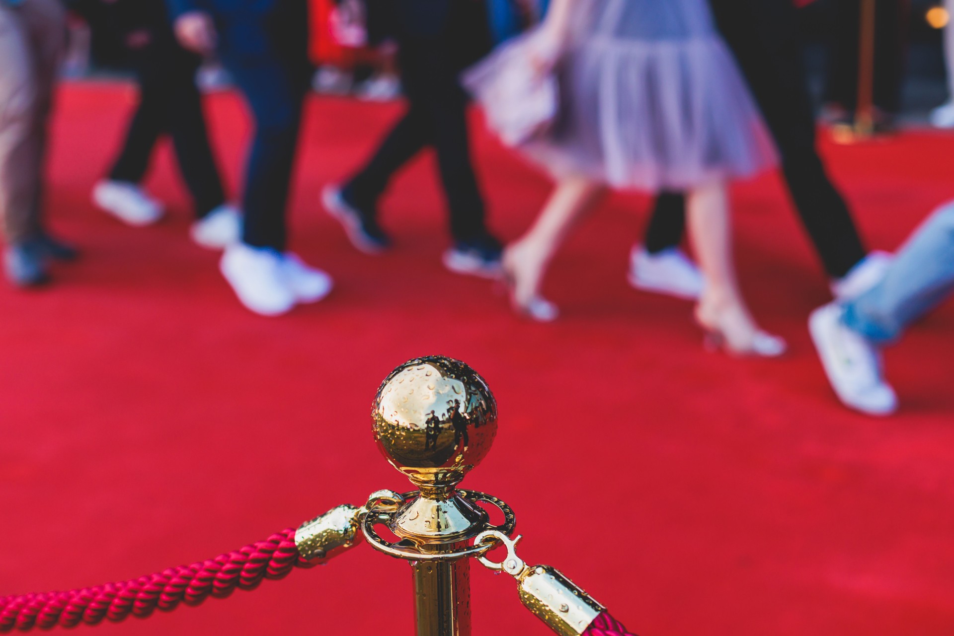 Red carpet with ropes and golden barriers on a luxury party entrance, cinema premiere film festival event award gala ceremony, wealthy rich guests arriving, outdoor decoration elements, summer day